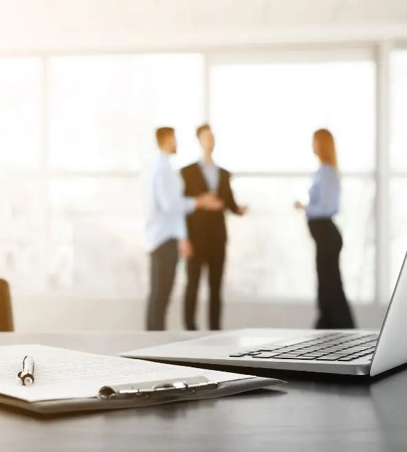 Harcèlement en entreprise. Alerte CSE : Un représentant du CSE alerte l'entreprise sur une potentielle situation de harcèlement au travail et souhaite qu'une enquête interne soit effectuée. Des documents et un ordinateur sont visibles sur le bureau, tandis que des collègues discutent en arrière-plan.